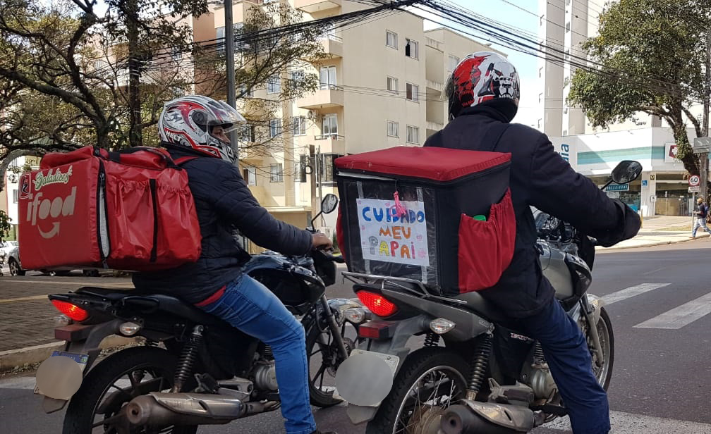 Imagem referente a “Cuidado: Meu Papai”; recado escrito em bolsa de entrega de motociclista chama atenção para o cuidado no trânsito