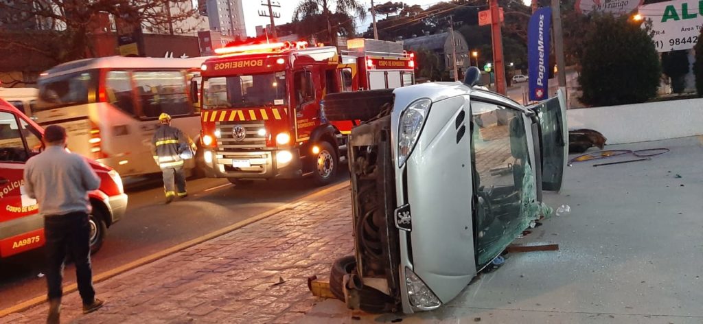 Motorista fica gravemente ferido após carro bater contra ônibus e capotar