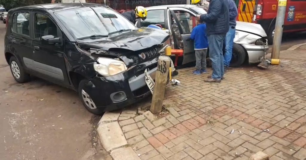 Veículos invadem calçada e atingem pilares de proteção após forte colisão ente Uno e Palio