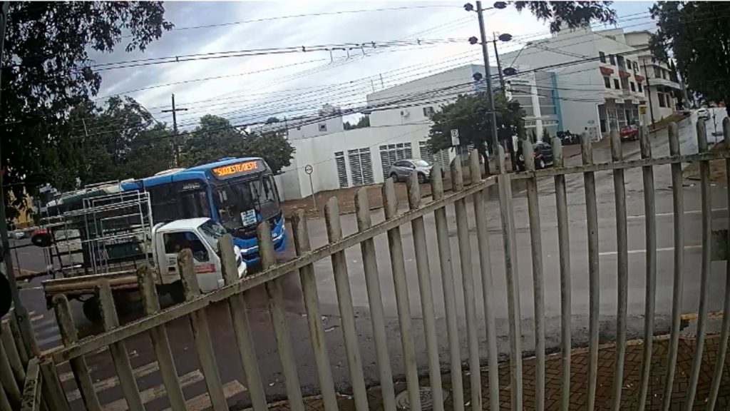 Câmera flagra colisão entre ônibus e caminhão, que é arremessado contra portão de imóvel
