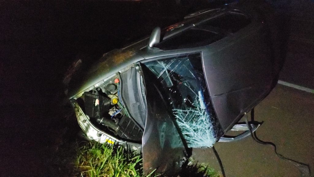 Siena capota após colidir com carreta carregada de madeira na BR-277; carga ficou espalhada