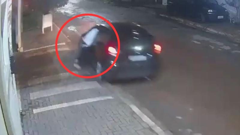 Criminoso fica pendurado na janela de carro e é arrastado por motorista