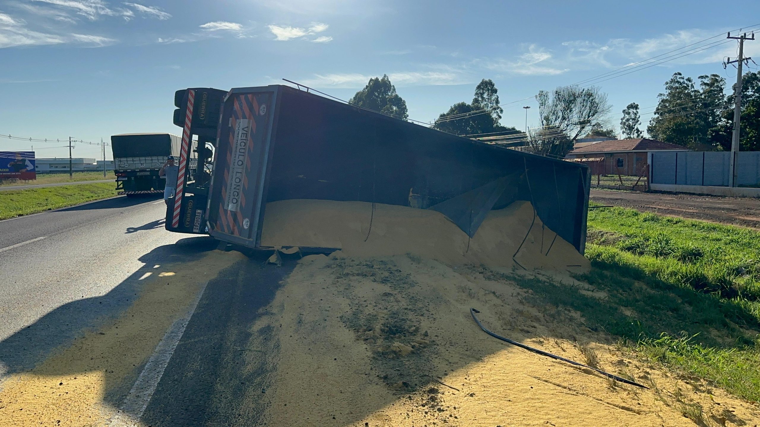 Semirreboque tomba na BR-277 em Cascavel e carga de farelo fica espalhada às margens da rodovia
