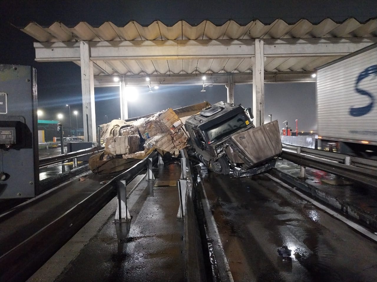 Caminhão tomba em cancela de pedágio na BR-116 e carga vai ao chão Caminhão tomba em cancela de pedágio na BR-116 e carga vai ao chão