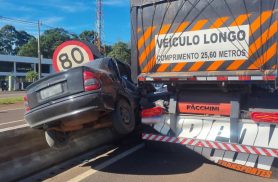 Corsa fica suspenso entre caminhão e mureta após acidente na BR-277, em Cascavel