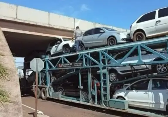Caminhão-cegonha preso sob viaduto causa lentidão na PR-323 Imagem referente a Caminhão-cegonha preso sob viaduto causa lentidão na PR-323