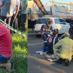 Imagem relativa a Homem se ajoelha e reza enquanto socorristas tentam salvar motociclista após grave acidente