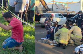 Homem se ajoelha e reza enquanto socorristas tentam salvar motociclista após grave acidente