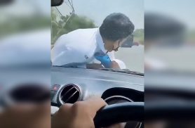 Agente de trânsito fica pendurado no capô de carro em Kanpur, na Índia
