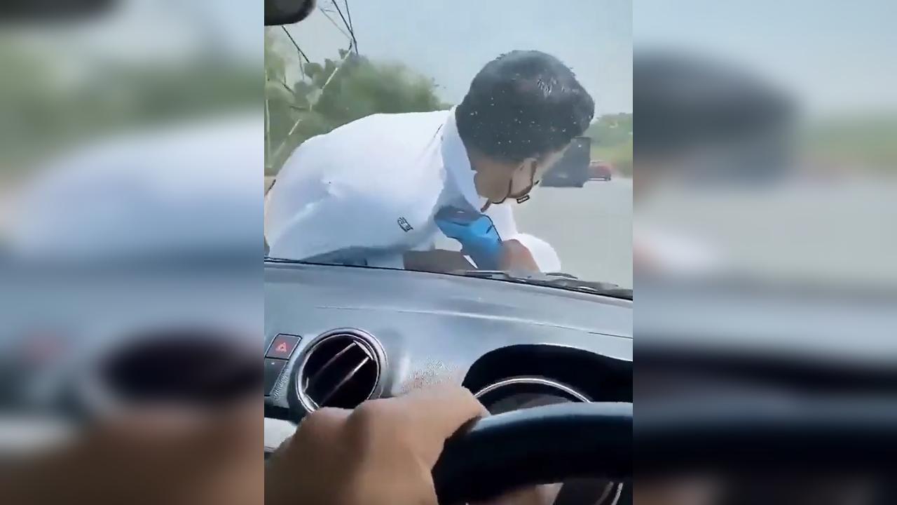 Agente de trânsito fica pendurado no capô de carro em Kanpur, na Índia